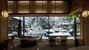 A traditional Japanese room with tatami flooring, wooden furniture, and a view of a snowy garden. - Hotel Yagi (Awara)