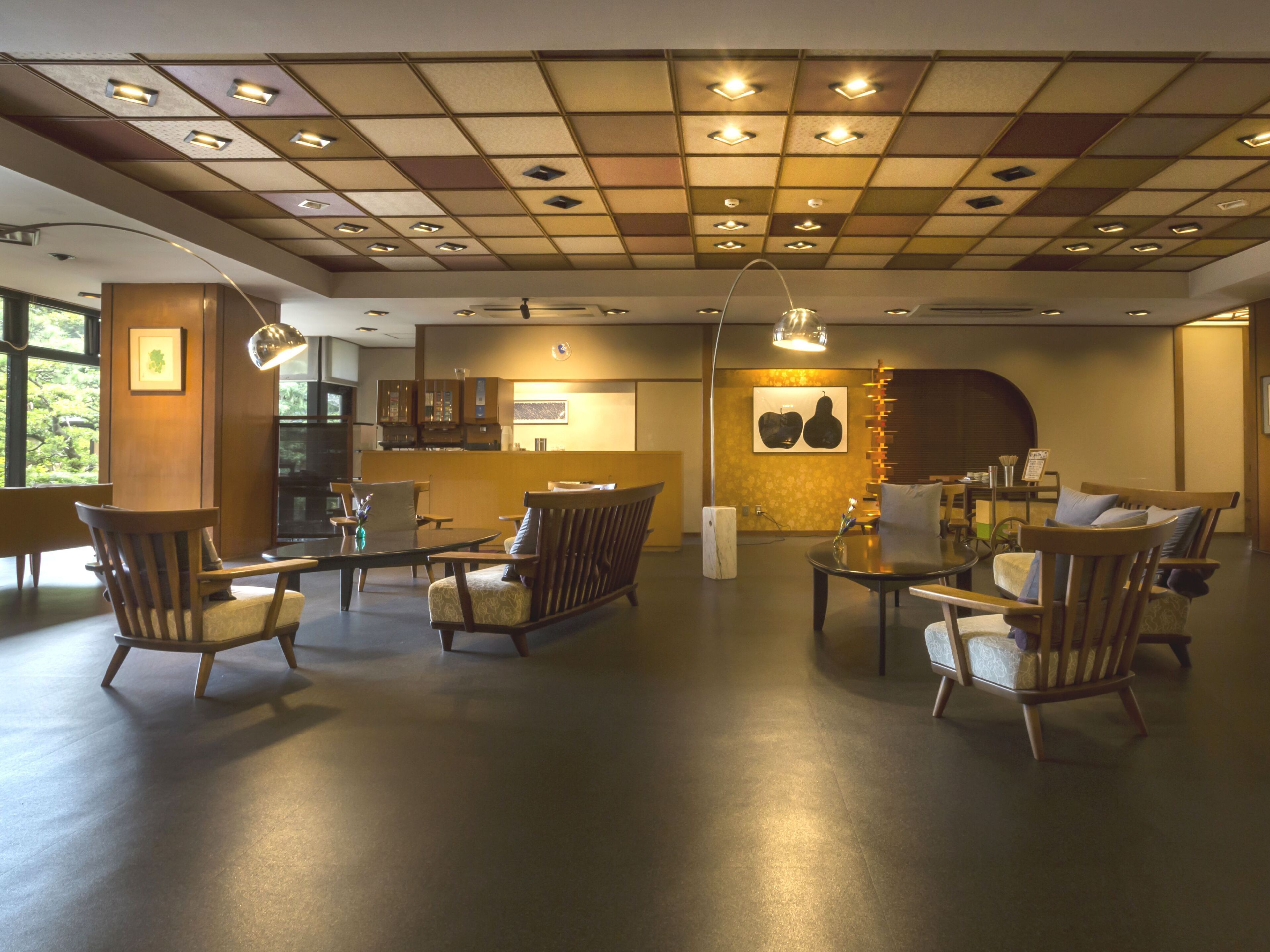Un hall d’entrée spacieux au design moderne, comprenant un mélange de meubles en bois et de meubles rembourrés, un comptoir d’accueil et un mur décoratif orné d’œuvres d’art.