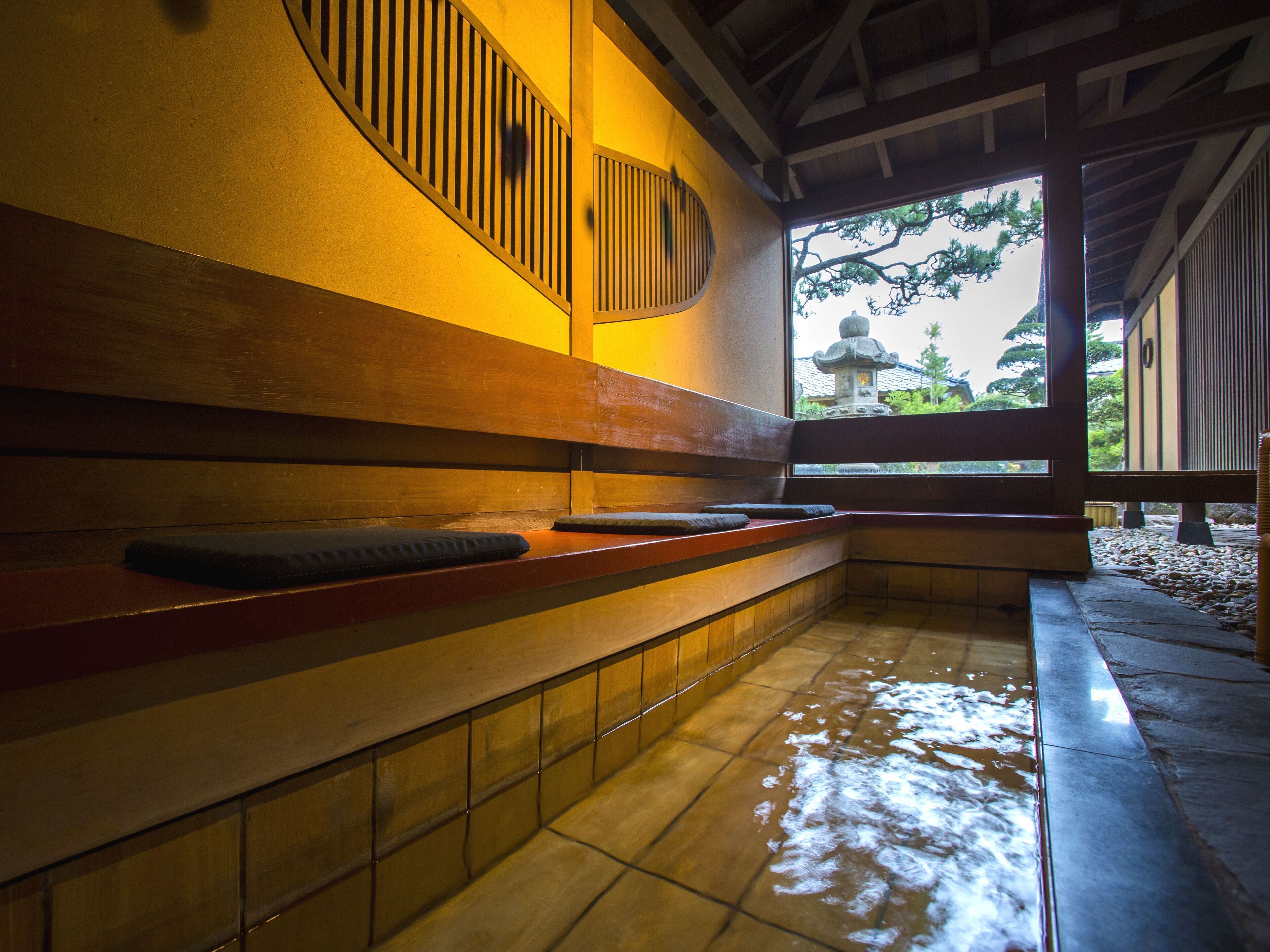 Una habitación japonesa tradicional con esteras de tatami, un banco de madera y vista a un templo a través de una ventana.