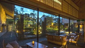 A serene indoor garden with wooden furniture and a view of the surrounding landscape. - Hotel Yagi (Awara)