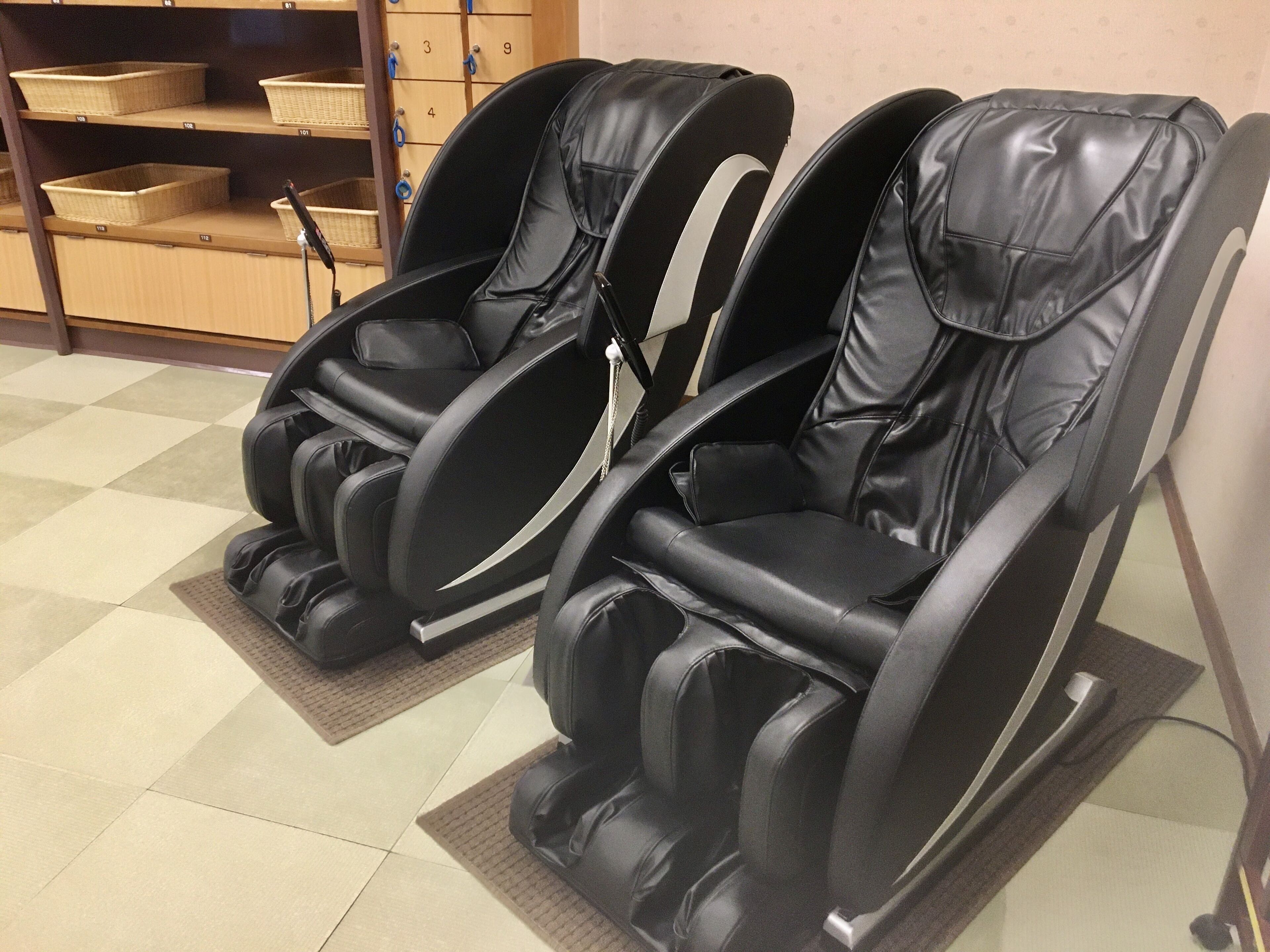 Zwei Massagesessel in einem Raum mit Schachbrettmuster und Regalen mit Körben.