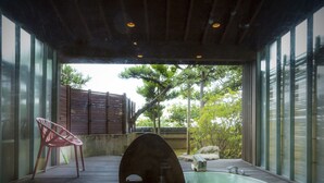 A spa area with a hot tub, wooden deck, and a chair. - Hotel Yagi (Awara)