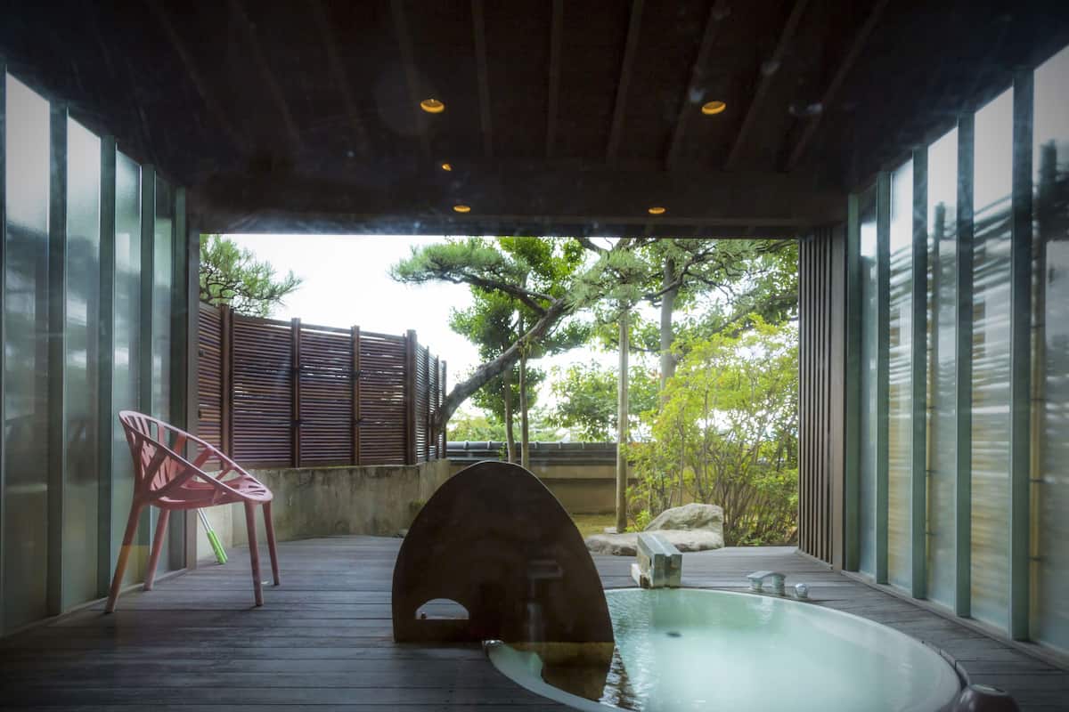 Área de spa com hidromassagem, deck de madeira e uma cadeira.