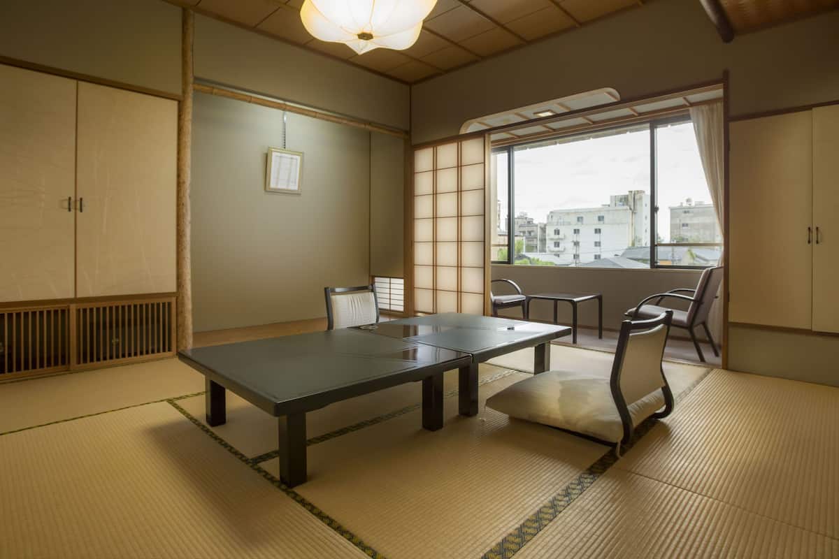 Um quarto japonês tradicional com tatames, uma mesa baixa e portas deslizantes.
