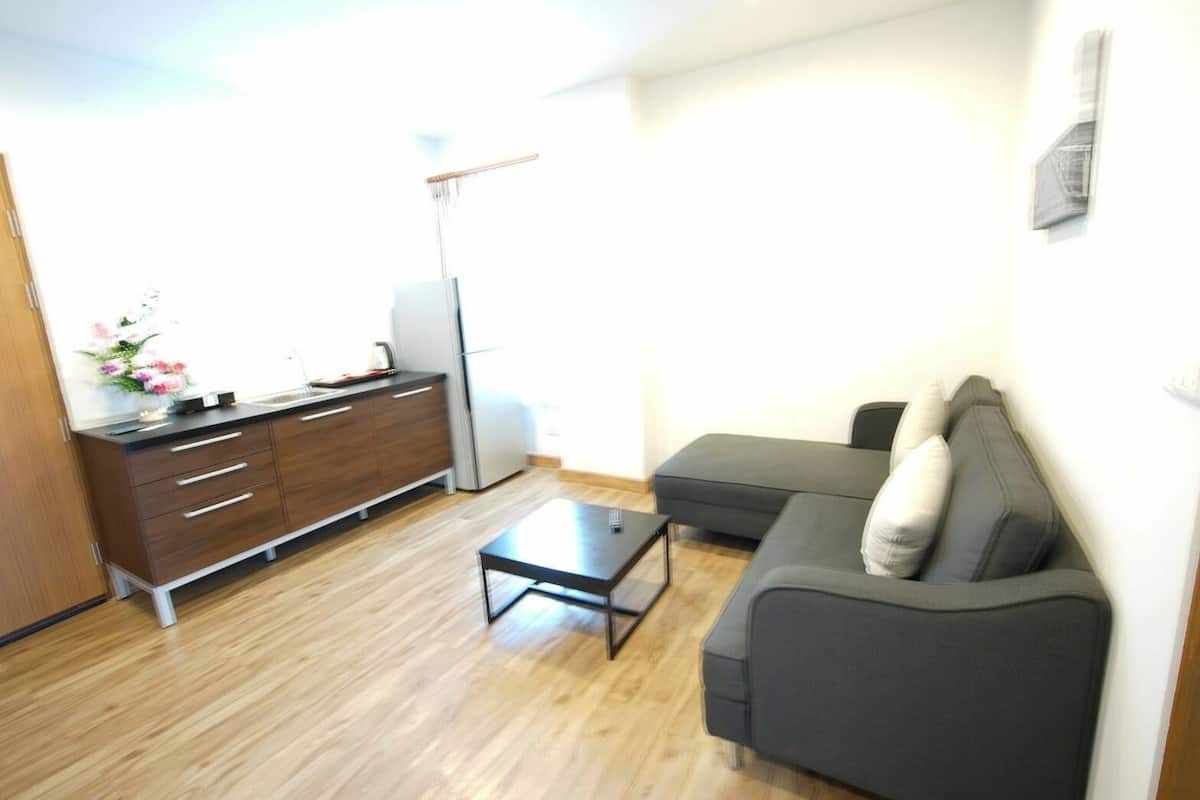 A compact living space with a kitchenette, a sofa, and a coffee table.
