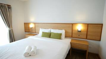 Habitación de hotel con una cama grande, dos mesitas de noche y cabecero con luces empotradas.