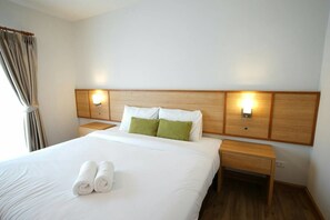 A hotel room with a large bed, two bedside tables, and a headboard with wall-mounted lights. - Donchan Residence (Chiang Mai)