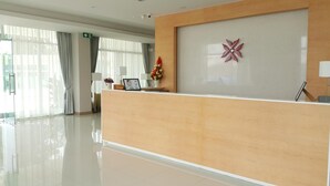A hotel reception area with a wooden reception desk, a decorative wall piece, and a sign that says "Welcome". - Donchan Residence (Chiang Mai)