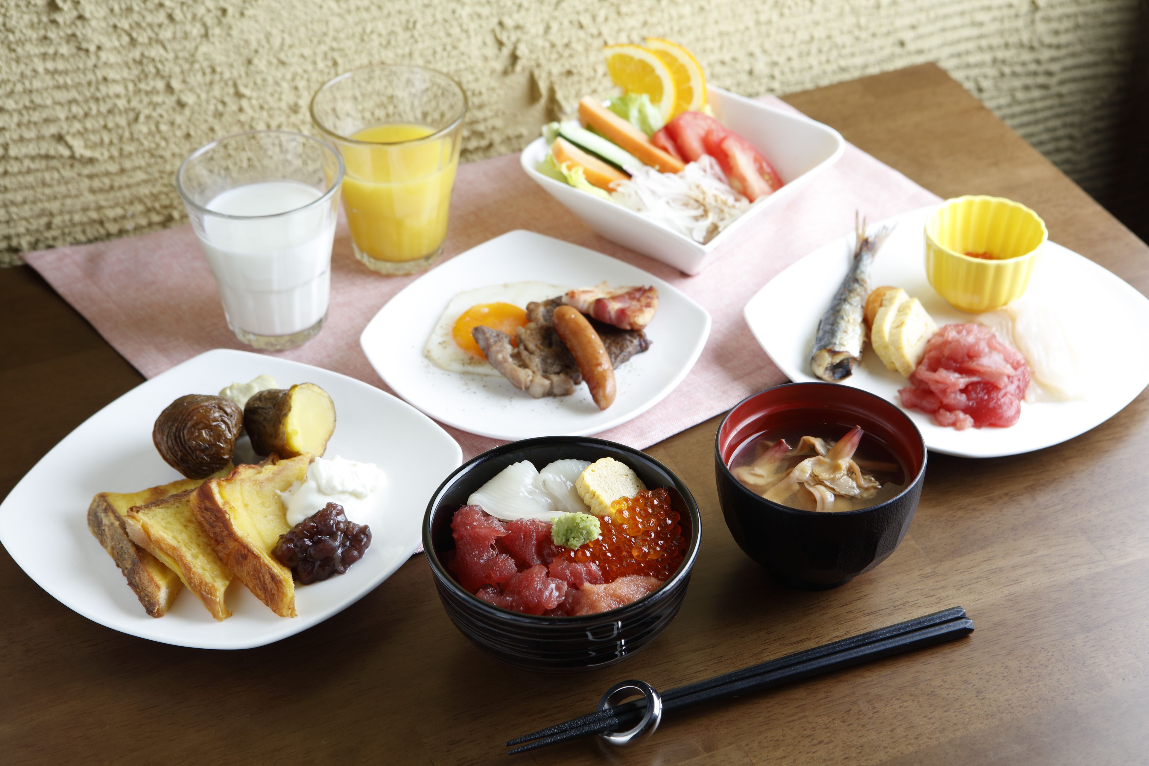 A table with various dishes including sushi, sashimi, and a bowl of soup.
