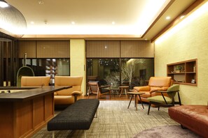 Una sala de estar moderna con sofá, sillón, reposapiés y una mesita.