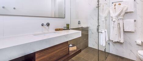 A modern bathroom with a marble vanity, a glass shower enclosure, and multiple white towels.