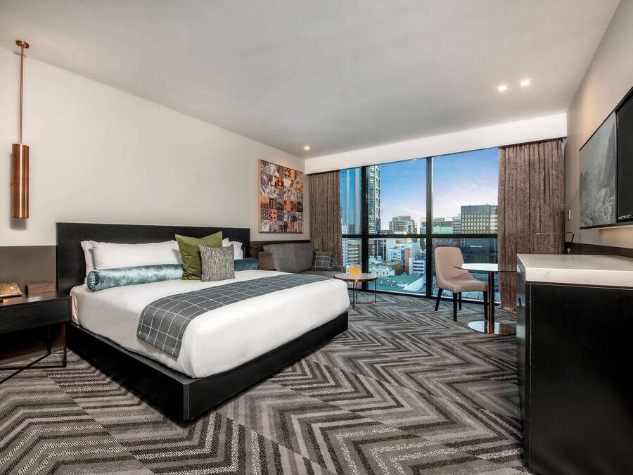 Una habitación de hotel moderna con una cama grande, un escritorio y vistas a la ciudad.
