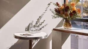 A round table with a vase of flowers, two glasses, and a menu.