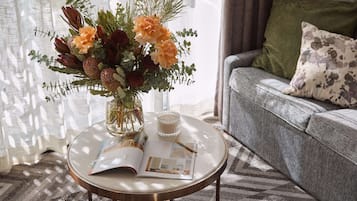 Una mesa de vidrio redonda con una revista, una vela y un arreglo floral.