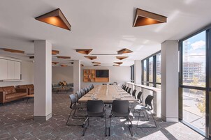 Una sala conferenze con un lungo tavolo, sedie e un'ampia finestra con vista sulla città.