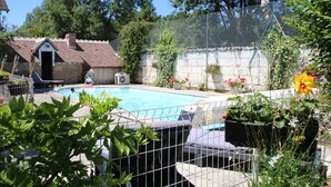 Ein Garten mit Pool, einer kleinen Gartenhütte und verschiedenen Pflanzen und Blumen.