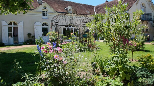 Ein Garten mit einem Pavillon, ein Gebäude mit Ziegeldach und ein Weg zum Eingang.
