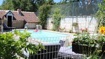 Una piscina al aire libre, sombrillas, sillones reclinables de piscina