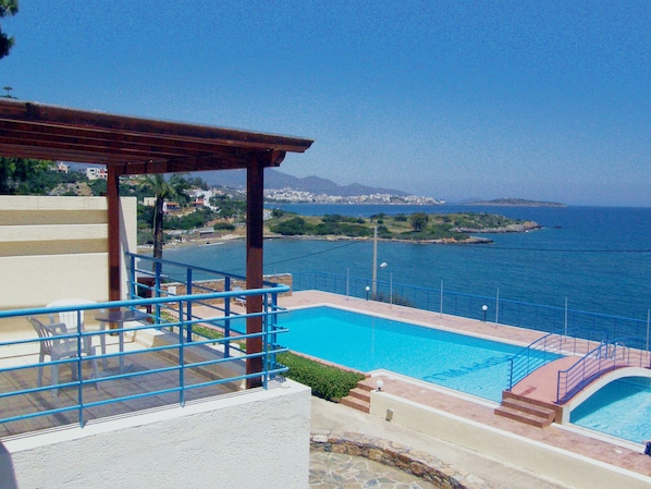 A pool with a view of the sea and a distant cityscape.