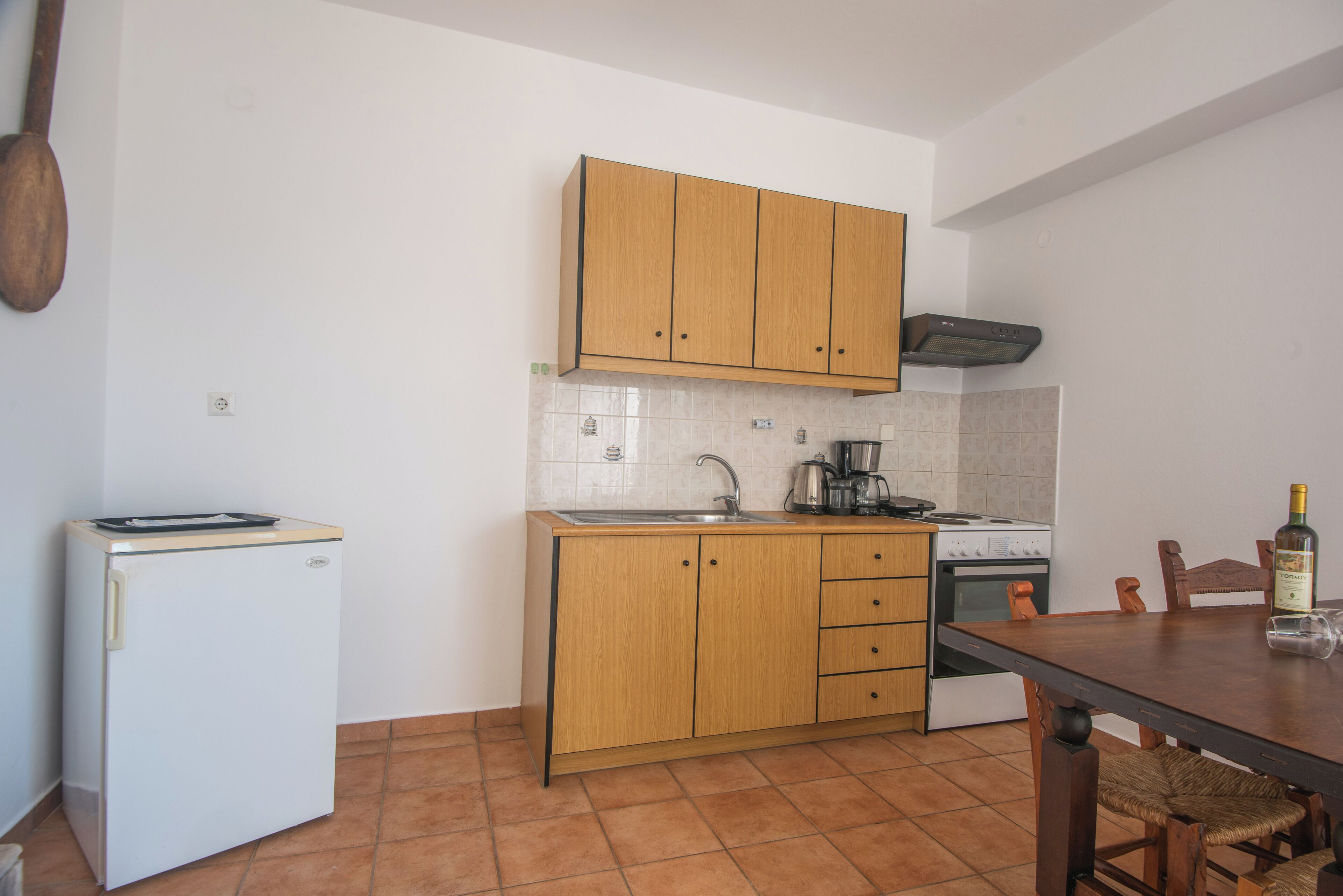 A compact kitchen with wooden cabinets, a white refrigerator, a stove, and a dining table.