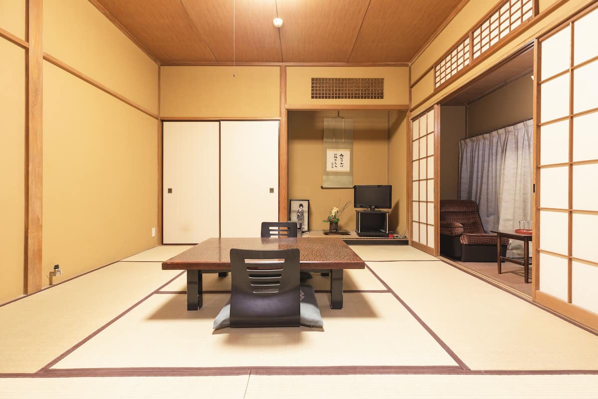 A traditional Japanese room with tatami flooring, a low table, and a sliding door.