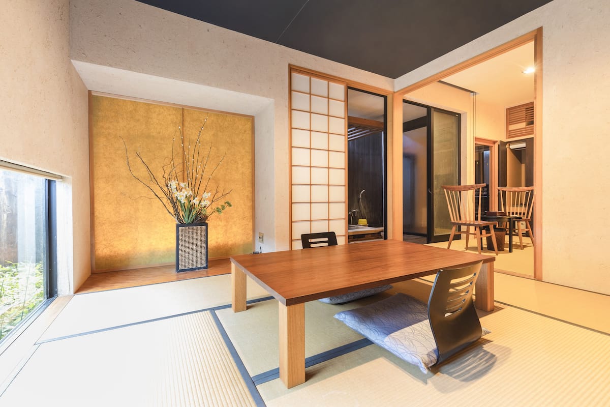 A traditional Japanese-style room with tatami flooring, a wooden dining table, and sliding doors.
