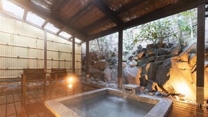 A hot spring area with a wooden deck, a stone hot tub, and a bamboo backdrop. - Yushintei (Hakone)