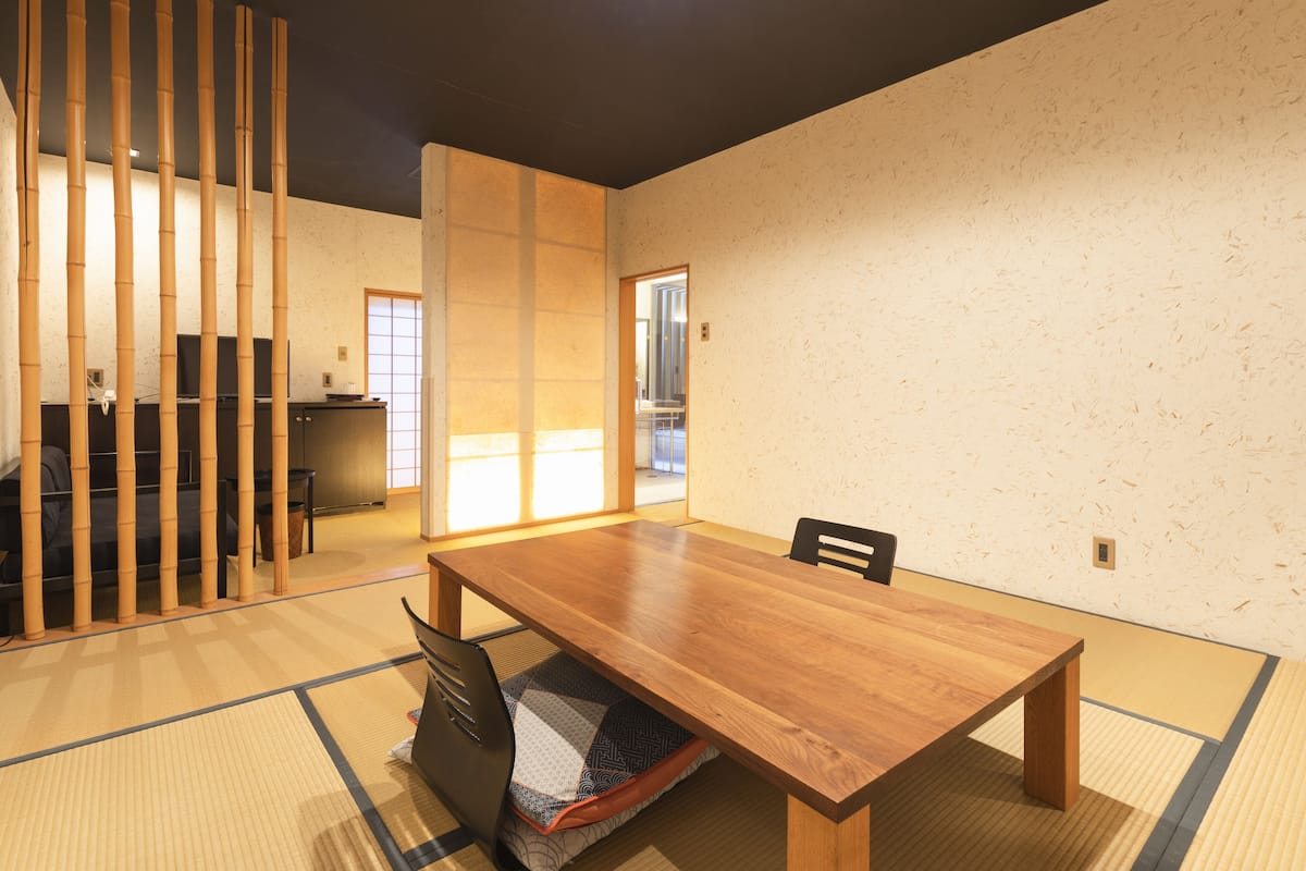 A traditional Japanese-style room with tatami flooring, a wooden table, and a sliding door.