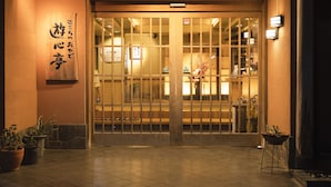 A traditional Japanese entrance with sliding doors, a sign with Japanese characters, and potted plants. - Yushintei (Hakone)