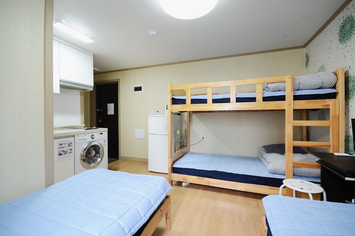 Un dormitorio con literas, lavadora y refrigerador.