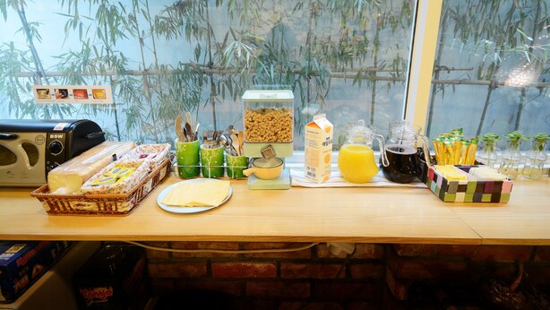 Une table en bois dressée pour le petit-déjeuner, avec un grille-pain, des céréales, du lait et divers autres aliments pour le petit-déjeuner.