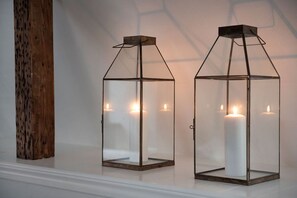 Two glass candle holders with candles on a white surface.