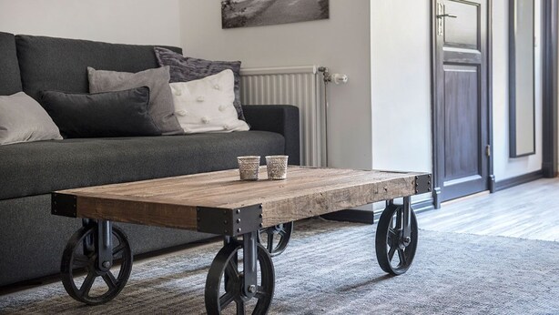 A modern living room with a sofa, a wooden coffee table with wheels, and a radiator. - Hotell Repet (Visby)