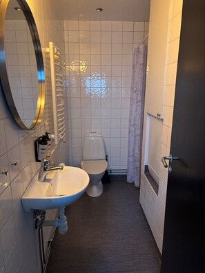 A compact bathroom with a white sink, a toilet, and a towel rack.