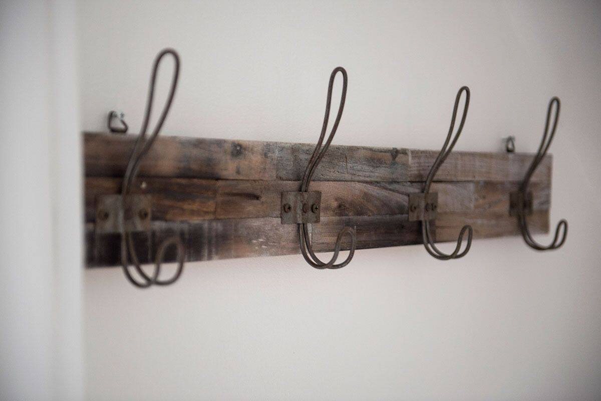 A rustic wall-mounted coat rack made of wooden planks and metal hooks.
