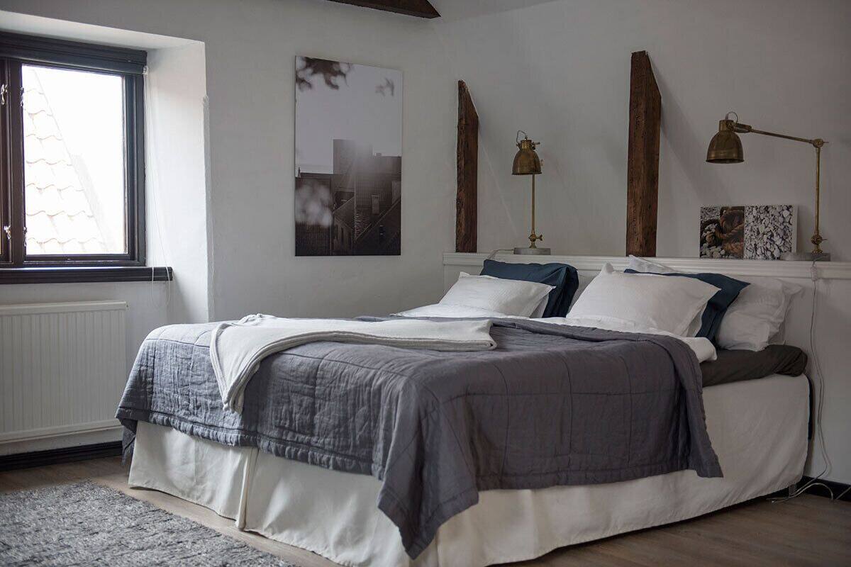 A bedroom with a bed, a window, and wall-mounted lamps.
