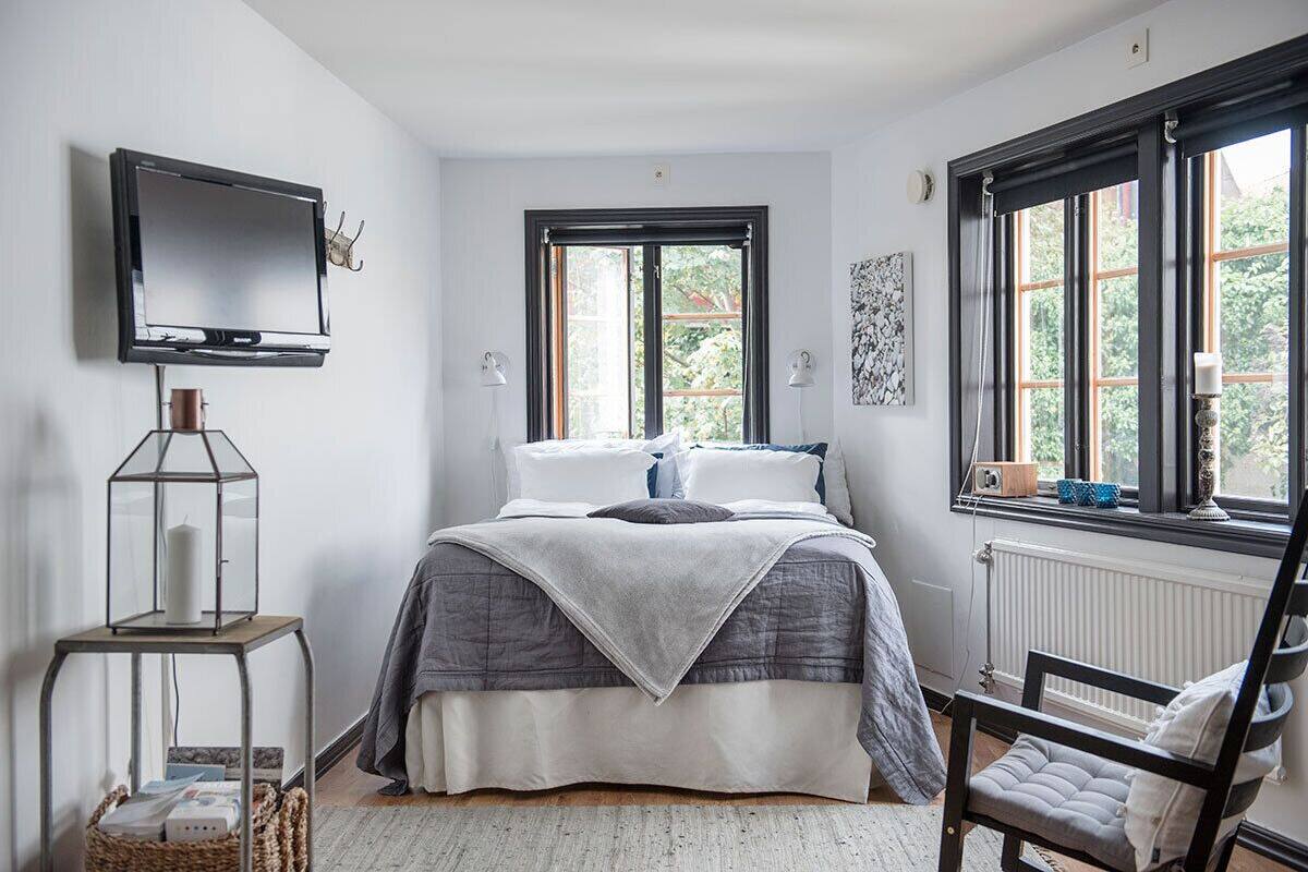 A bedroom with a bed, a television, a window, and a chair.