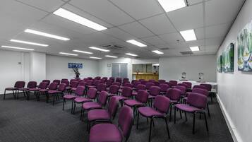 A conference room with rows of purple chairs, a white table, and a wooden podium.