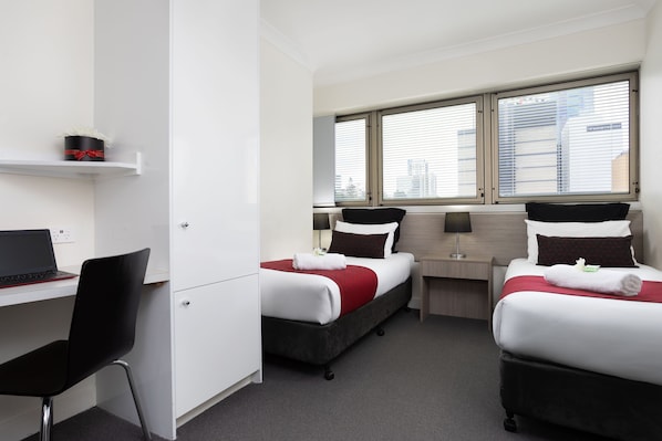 Habitación de hotel con dos camas, un escritorio y una silla.
