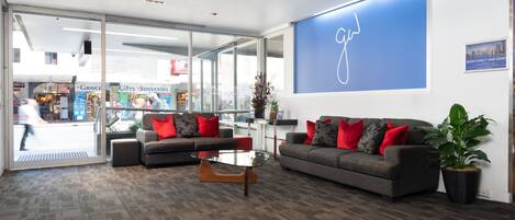 En moderne reception med to sofaer, et sofabord og en stor blå væg med et logo.