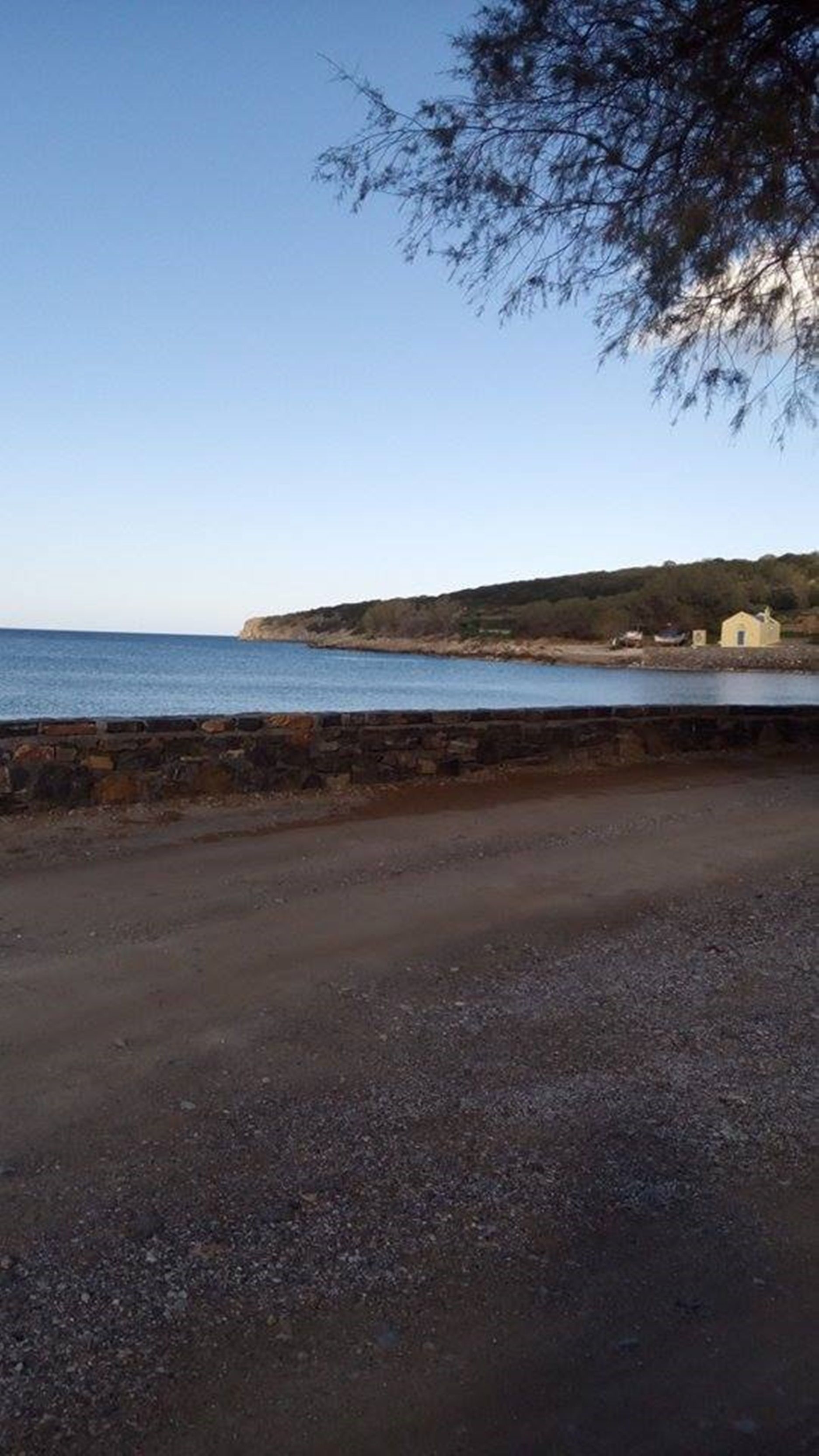 Une route côtière bordée d’un mur de pierres et offrant une vue sur la mer.