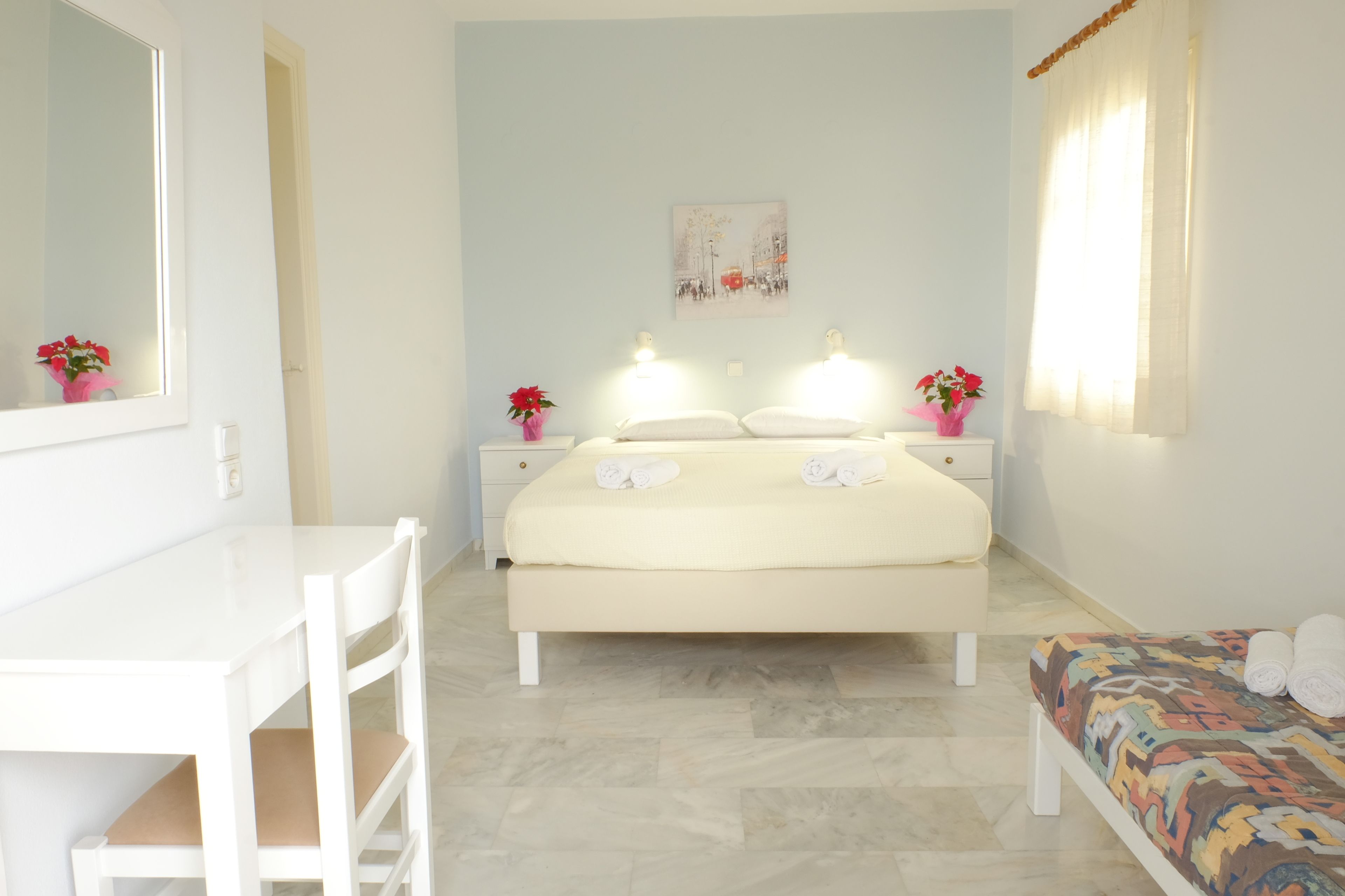 A bedroom with a bed, bedside tables, a desk, and a chair.