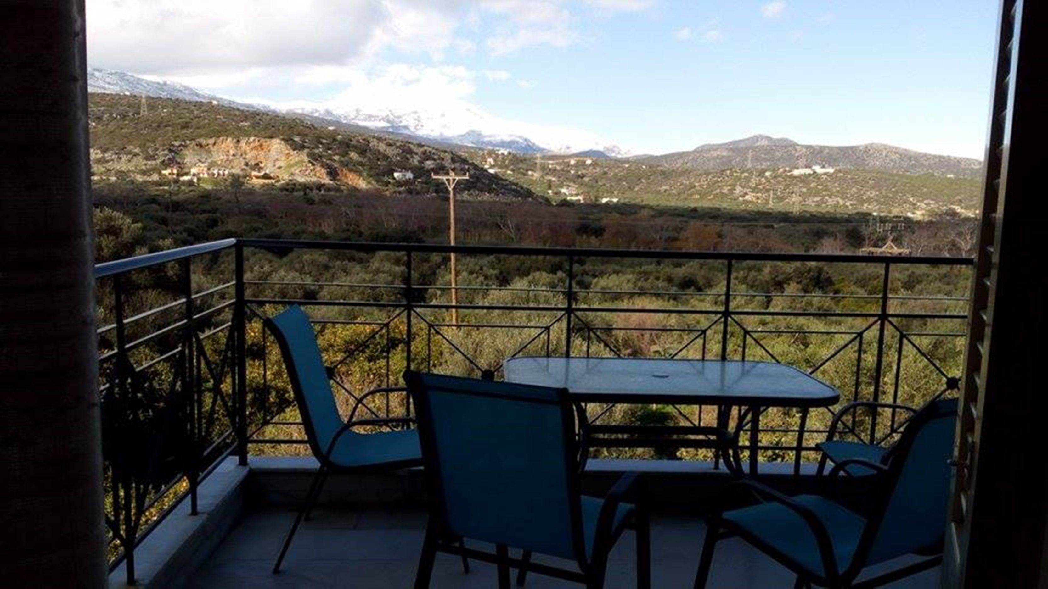 Un balcon doté d’une table et de chaises, offrant une vue sur un paysage montagneux.