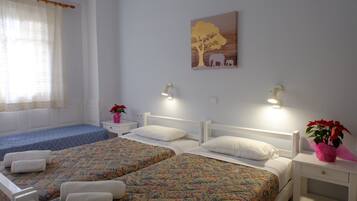 A bedroom with two beds, a window with curtains, a wall painting, bedside lamps, and a nightstand with a plant.