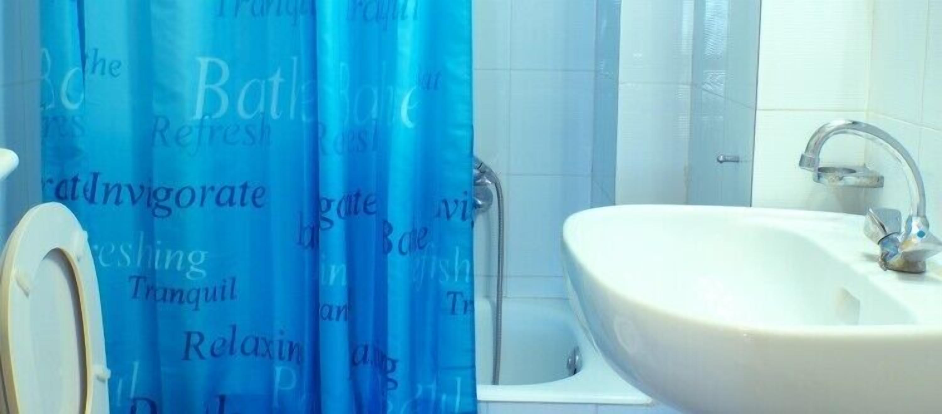 A bathroom with a white sink, a shower curtain with text, and a white toilet.
