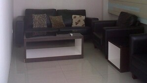 A living room with a black sofa, a white coffee table, and a green ceiling. - Hotel Pagi (Labuan Bajo)