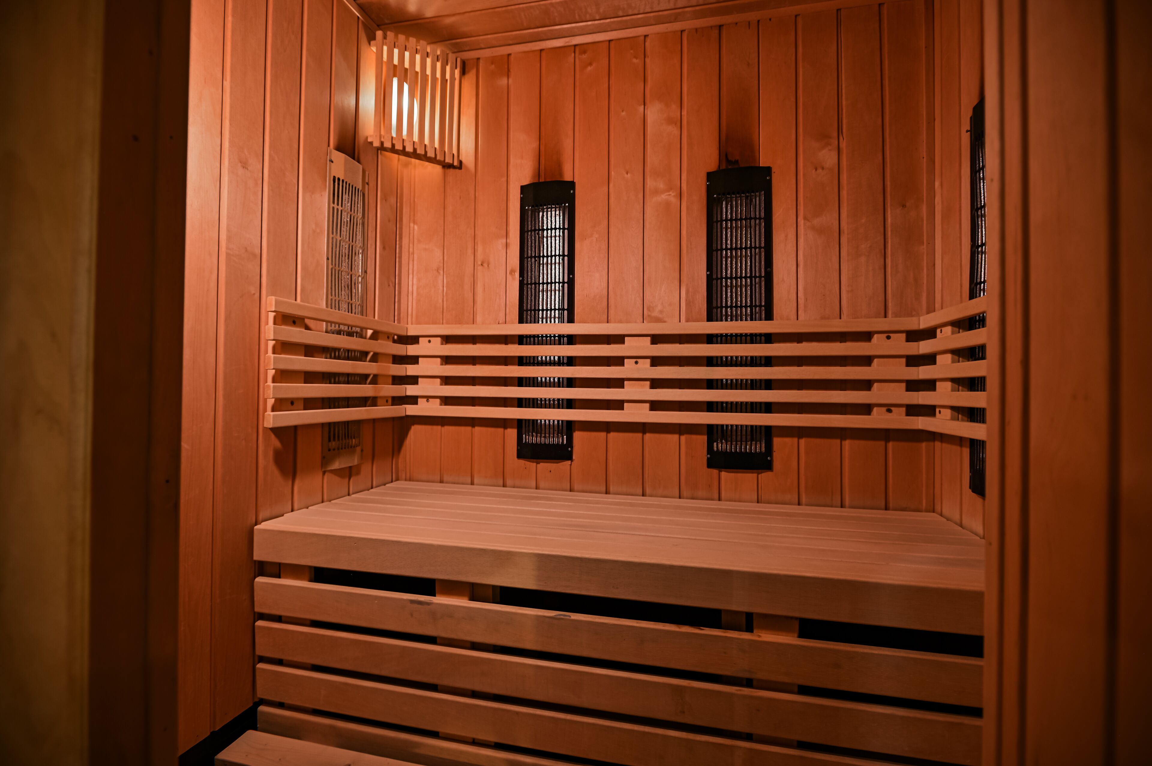 A sauna with wooden benches and black ventilation windows.