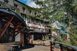 A hotel with outdoor seating, stone walls, and a sign reading 'Hotel'. - Šport Hotel Donovaly (Donovaly)