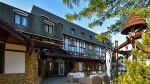 Een hotel met een restaurant op de begane grond, terras en een traditionele Europese architectuur.