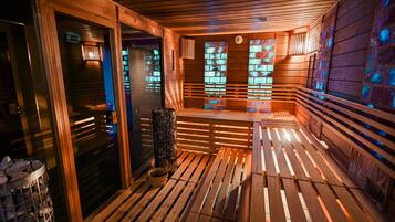 Una sauna con bancos de madera y piso de baldosas, que incluye una puerta de cristal y una pared de piedra.